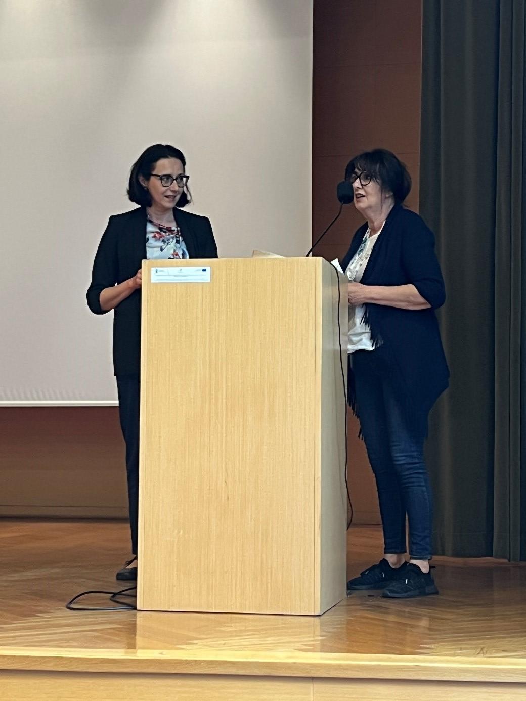 dr Adrianna Sarnat-Ciastko oraz dr hab. Marzena Bogus-Spyra przy m&oacute;wnicy podczas podsumowania warsztatu arteterapeutycznego &bdquo;O!Chronię&rdquo; realizowanego w ramach Dnia Dydaktyki 2026