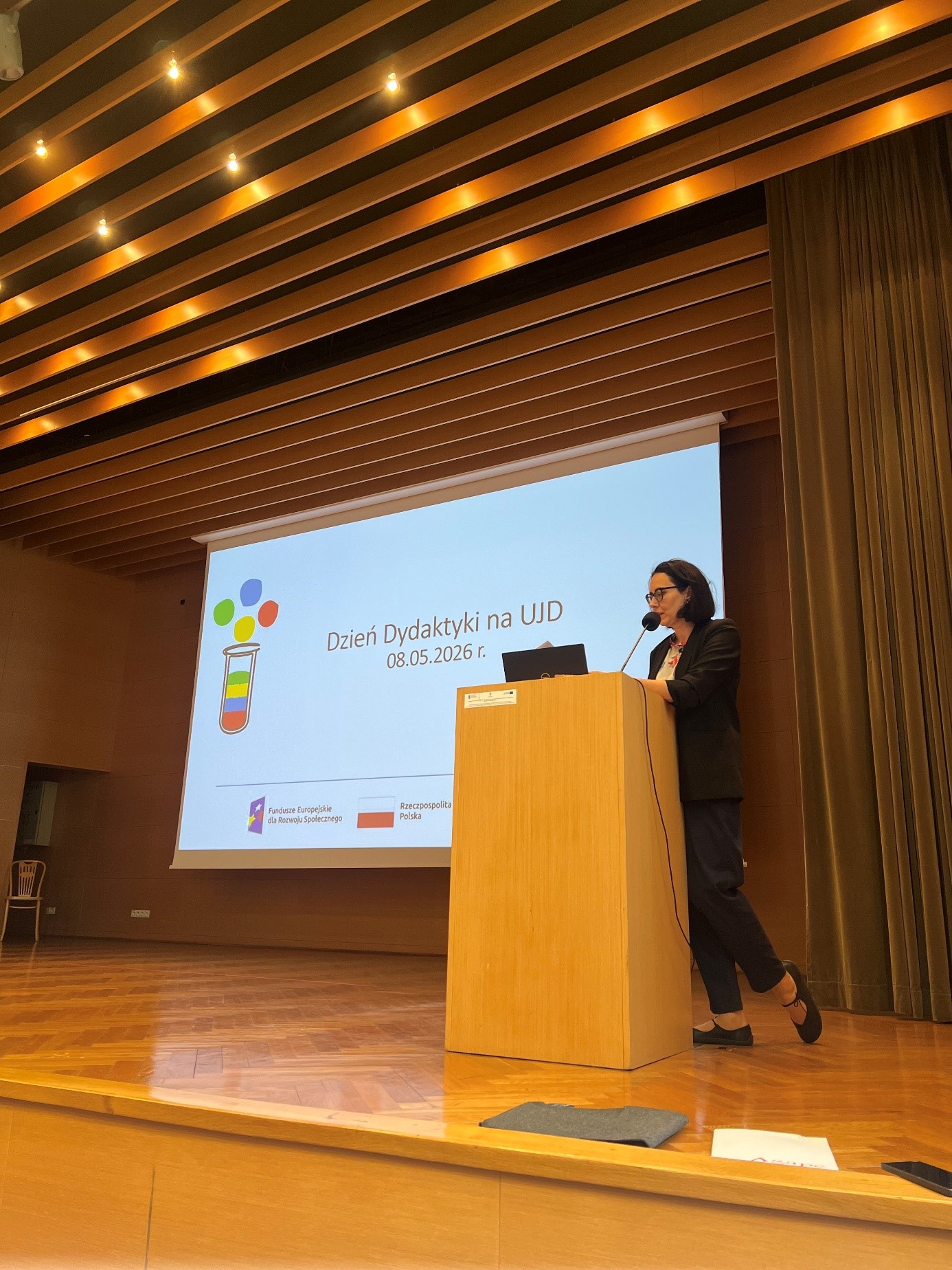 dr Adrianna Sarnat-Ciastko rozpoczyna Dzień Dydaktyki 2026 na UJD, a w tle prezentacja z napisem &bdquo;Dzień Dydaktyki na UJD 08.05.2026 r.&rdquo;.