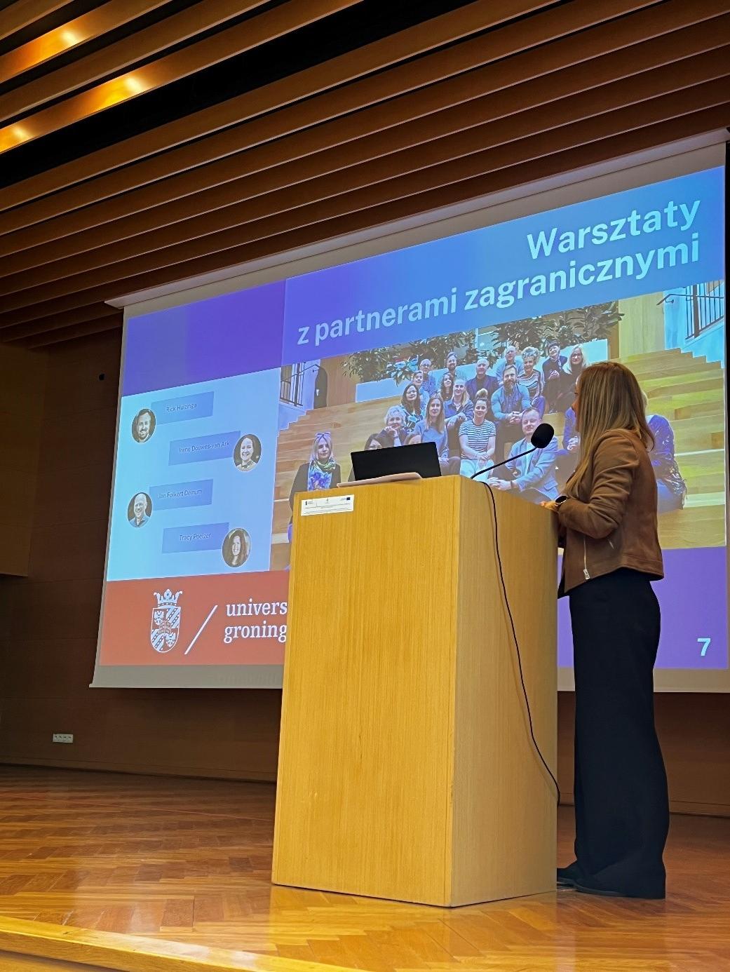dr Anna Irasiak prezentuje założenia projektu „UJDydaktyka”. W tle widoczna prezentacja dotycząca warsztatów realizowanych z partnerami zagranicznymi dr Anna Irasiak prezentuje założenia projektu „UJDydaktyka”. W tle widoczna prezentacja dotycząca warsztatów realizowanych z partnerami zagranicznymi